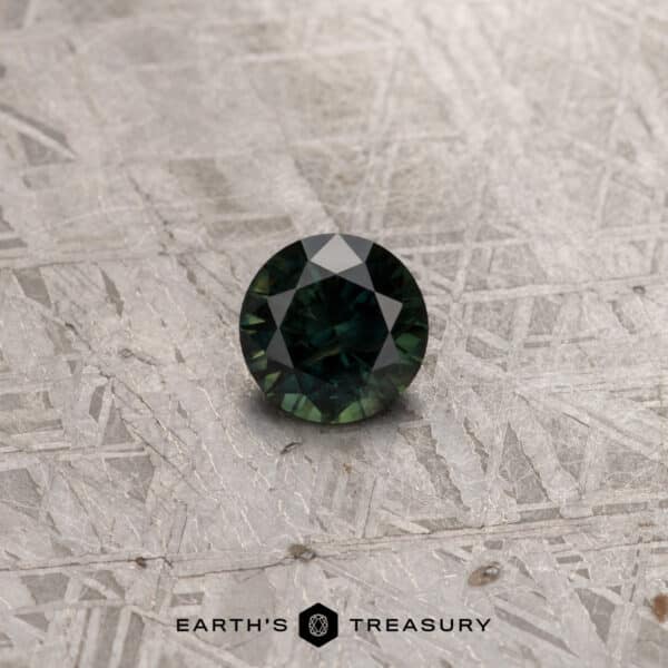 A 2.91-carat khaki green Australian sapphire (heated), round with faceted cuts, is placed on a textured, metallic surface. The background features a geometric linear design, and the bottom center displays the logo and text "Earth's Treasury.