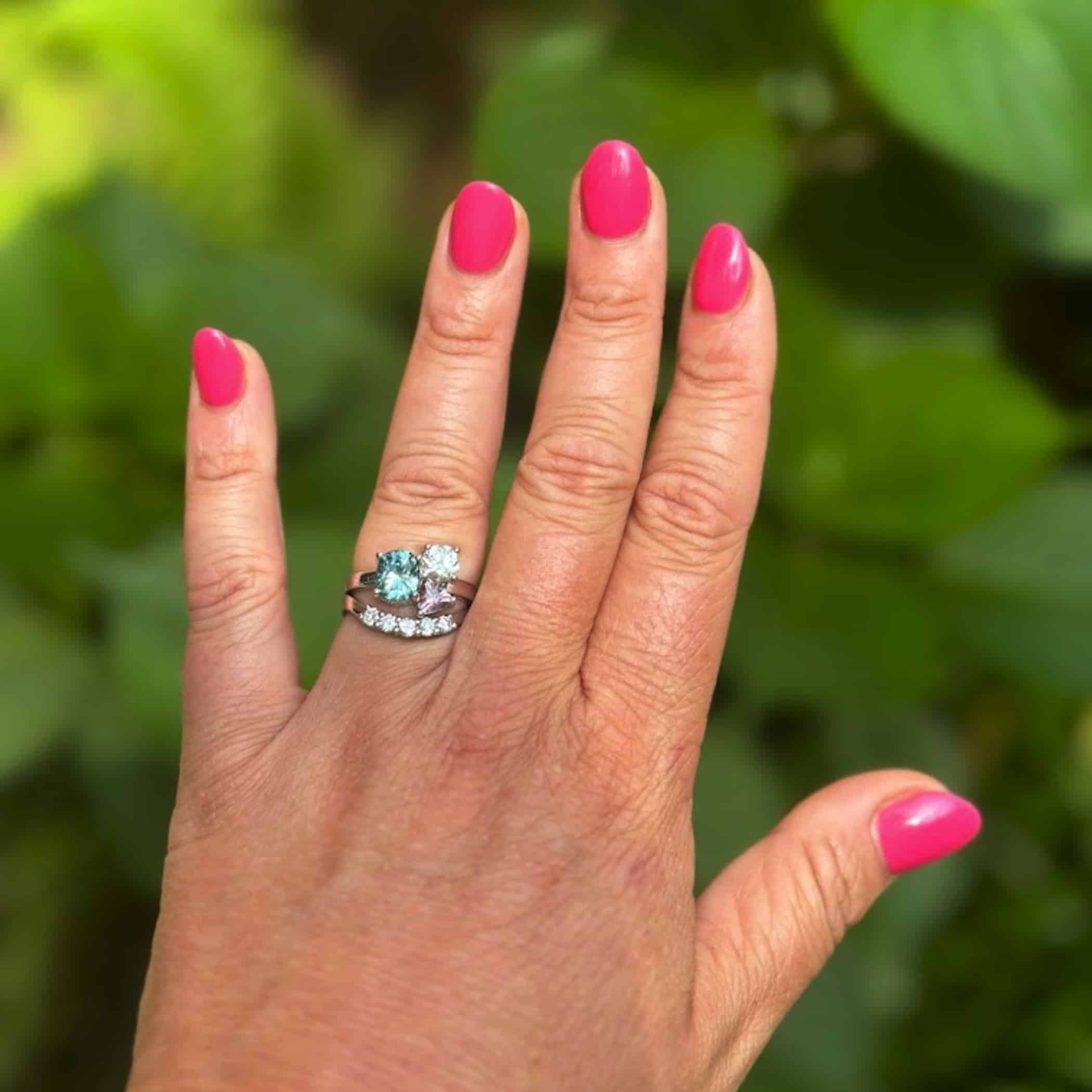 A photo from a customer review featuring a custom ring set in 14k white gold, featuring heirloom diamonds, a 2.08-carat teal sapphire, and a 0.65-carat pink sapphire