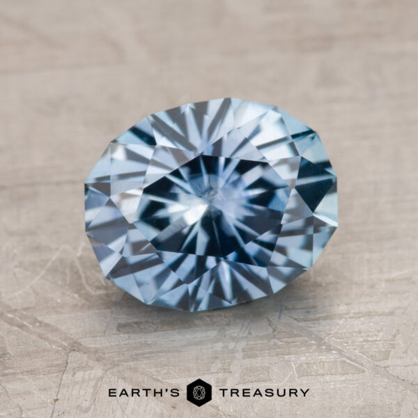 A 2.24-carat, heated Montana sapphire showcased on a textured surface with "Earth's Treasury" inscribed at the bottom.