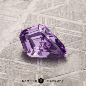 A 1.09-carat light purple sapphire rests on a textured surface. The text "EARTH'S TREASURY" appears at the bottom of the image.