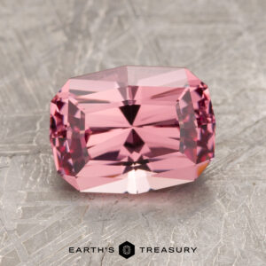 A polished 2.48-carat Tanzanian spinel with a rectangular shape and multiple facets displayed on a textured surface. Text reads "EARTH'S TREASURY" at the bottom.