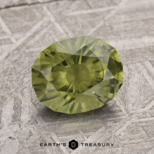 A 1.95-carat olive green Australian sapphire, cut in a faceted design, is displayed on a textured background. The logo "Earth's Treasury" is placed at the bottom of the image.