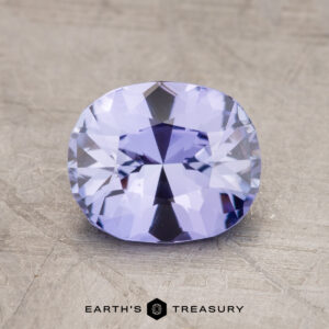 A 1.74-carat cushion-cut lavender Ceylon Sapphire (Heated) is displayed on a textured background. The text "EARTH'S TREASURY" appears at the bottom.