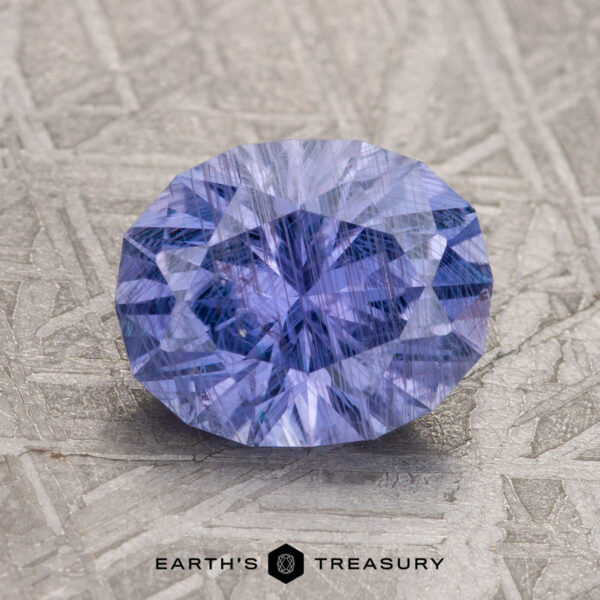 A 2.31-carat Violet Umba Sapphire is showcased on a textured surface with the text "Earth's Treasury" below it.