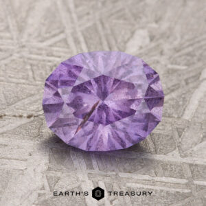 A splendid 1.98-carat light purple Umba Sapphire showcased on a textured surface, with the words "Earth's Treasury" emblazoned at the bottom.