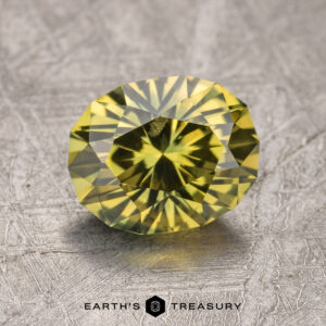 A 2.23-carat Australian yellow sapphire, featuring finely cut facets, rests on a textured surface with the logo "Earth's Treasury" displayed at the bottom.