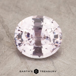 A close-up image of a 2.32-Carat faceted oval sapphire with a light pink hue, set against a textured neutral background. The logo for "Earth's Treasury" is visible at the bottom center of the image.