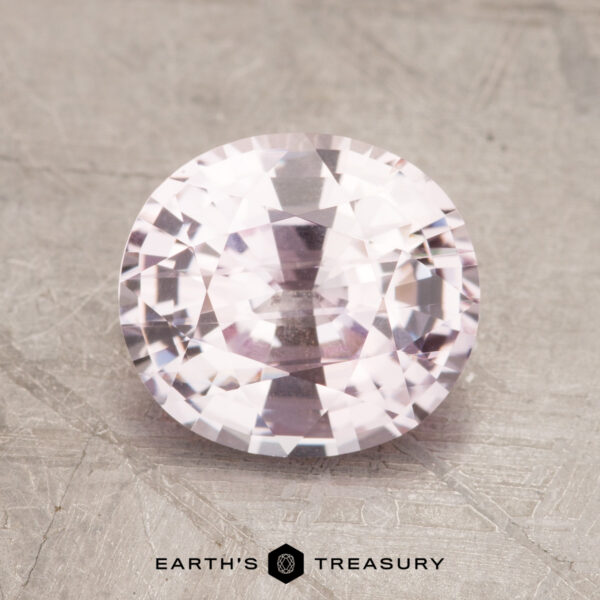 A 2.31-carat faceted, oval-cut light pink sapphire displayed on a textured gray surface with the "EARTH'S TREASURY" logo beneath it.