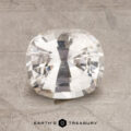 A 2.23-carat, cushion-cut white sapphire rests elegantly on a textured gray surface, adorned with the "Earth's Treasury" logo at the bottom.