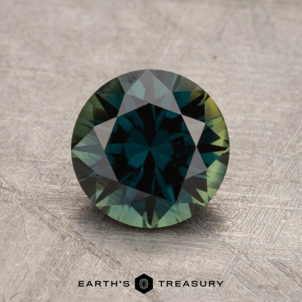 A 1.68-carat, round-cut Australian sapphire with a teal hue is showcased on a textured backdrop, featuring the text "Earth's Treasury" at the bottom of the image.