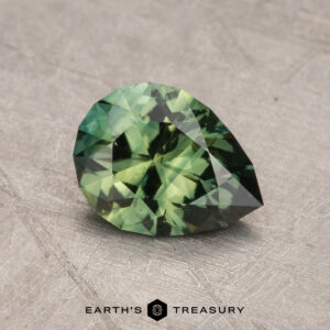 A pear-shaped, faceted 1.31-carat Australian Sapphire on a textured surface. The image includes the text "Earth's Treasury" at the bottom.