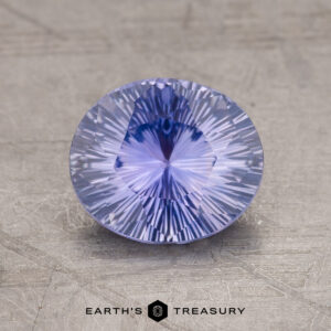 Displayed on a textured surface, a round 1.76-Carat Ceylon Sapphire with intricate facets captures the eye while the words "Earth's Treasury" appear at the bottom.