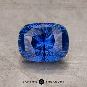 A close-up image of a 1.97-carat Ceylon Sapphire with intricate internal patterns, set against a textured gray background. Text at the bottom reads "EARTH'S TREASURY.