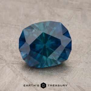 A 2.16-carat heated hexagon-cut Montana sapphire displayed on a textured surface with the logo "Earth's Treasury" below it.