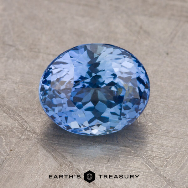 Close-up image of a faceted oval-blue 2.34-Carat Sapphire displayed on a textured surface, with the text "Earth's Treasury" below it.