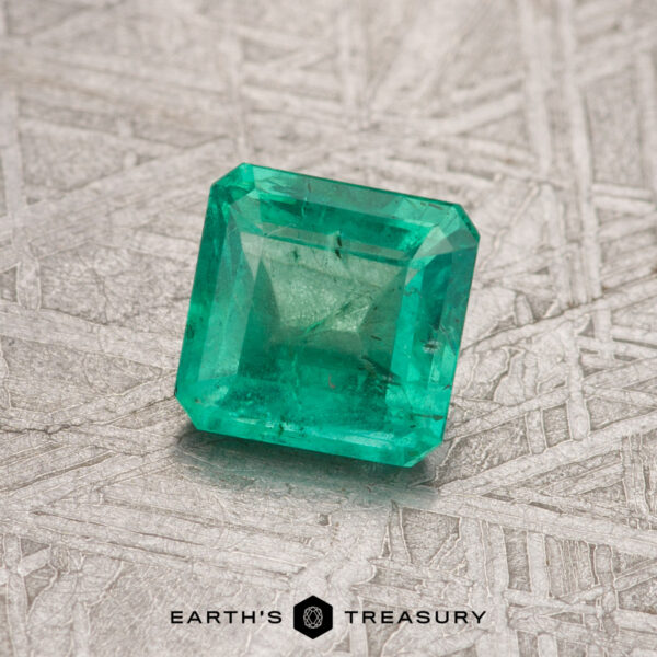 A square-cut green emerald gemstone, specifically a 0.70-carat Colombian emerald (treated), set against a textured gray background with the "Earth's Treasury" logo text at the bottom.