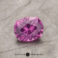 A faceted gemstone from product ET1127, featuring a pink hue, displayed on a textured gray surface.