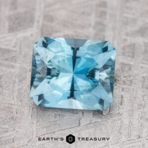 A 1.78-carat Nasarawa teal aqua gemstone, rectangular in shape with facets, displayed on a textured gray surface.