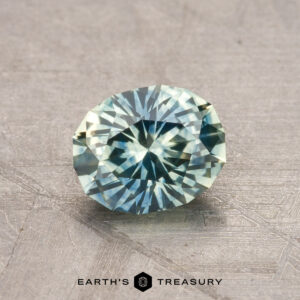 A 1.21-carat, oval-cut Montana Sapphire showcased on a textured background with "Earth's Treasury" inscribed beneath it.