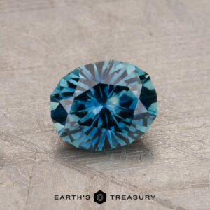 A 1.19-carat Montana sapphire (heated) with intricate faceting sits on a textured surface.