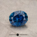 A faceted blue 1.14-carat Montana sapphire (heated) displayed on a textured surface with the logo "Earth's Treasury" at the bottom.