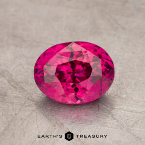 A faceted 1.70-carat heat-treated ruby displayed against a textured background with the text "Earth's Treasury" at the bottom.