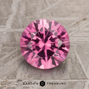 2.16-carat hot pink spinel with facets, resting on a textured surface.