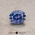 A 0.86-carat Montana sapphire (heated), expertly cut in a round brilliant shape, rests on a textured surface with "Earth's Treasury" elegantly inscribed at the bottom.