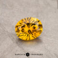 A round, faceted yellow 0.86-carat Montana sapphire (heated) displayed on a textured surface.