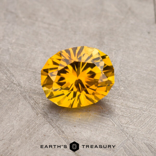 A round, faceted yellow 0.86-carat Montana sapphire (heated) displayed on a textured surface.