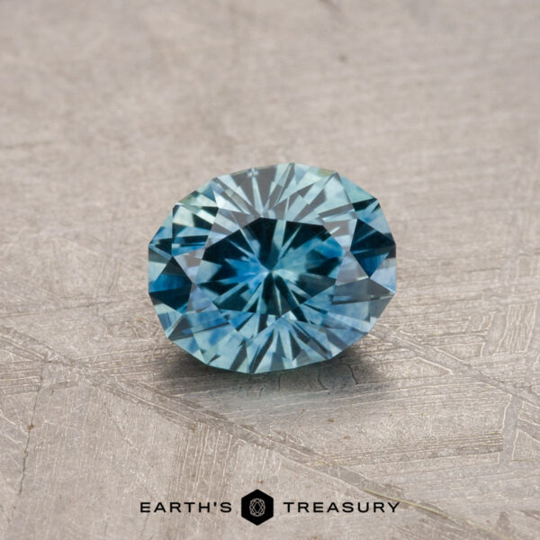 The 0.82-carat heated Montana Sapphire sits atop a textured surface, displaying its faceted blue beauty.