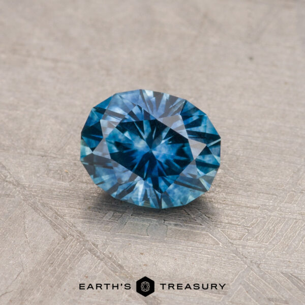 A brilliantly faceted 0.81-Carat Montana Sapphire, glistening blue against a textured gray backdrop, with the words "Earth's Treasury" elegantly displayed at the bottom.