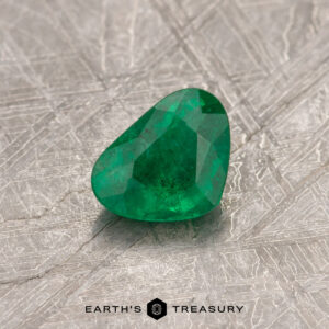 A 0.49-carat Colombian emerald gemstone resting on a textured surface with the text "Earth's Treasury" below it.