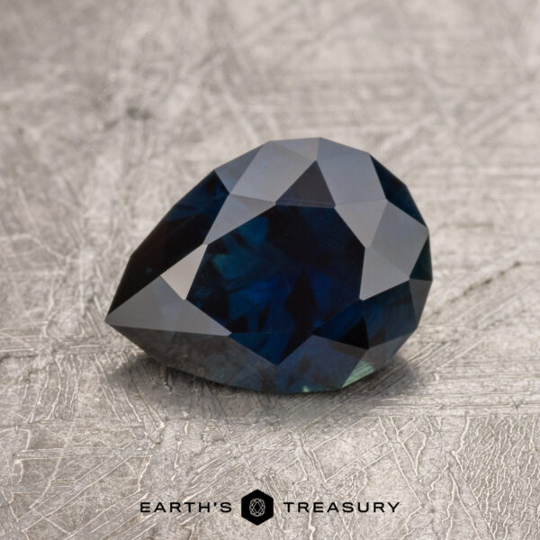 1.71-carat teardrop-shaped Midnight Blue Australian Sapphire on a textured gray surface.