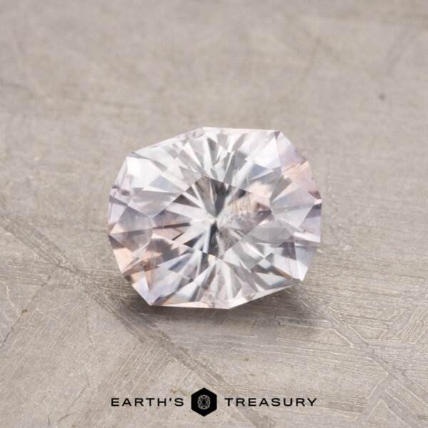 A 1.16-carat Montana sapphire on a textured surface with the logo "Earth's Treasury" underneath.