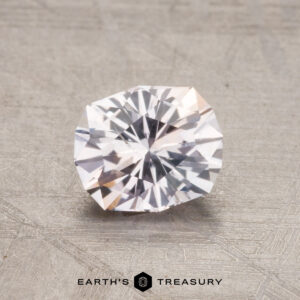 A 1.16-carat heated Montana sapphire with a reflective surface sits on a textured gray background.