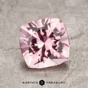 A square-cut gemstone with intricate facets rests on a textured surface, featuring the Earth's Treasury logo at the bottom.