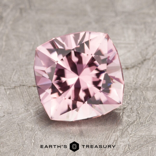 A square-cut gemstone with intricate facets rests on a textured surface, featuring the Earth's Treasury logo at the bottom.