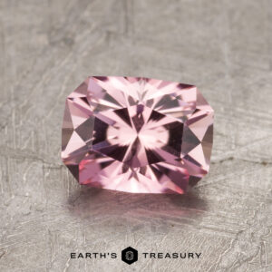 The ET1627 is a pink gemstone featuring a rectangular cushion cut displayed on a textured gray surface.