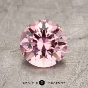 ET1635 gemstone resting on a textured gray surface with the "Earth's Treasury" logo.