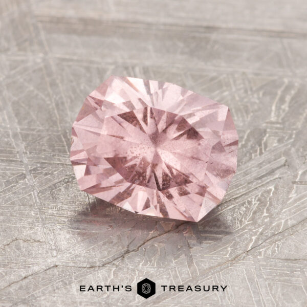 1.79-Carat Pastel Pyrope Garnet gemstone set on a textured gray surface, featuring the logo "Earth's Treasury" at the bottom.