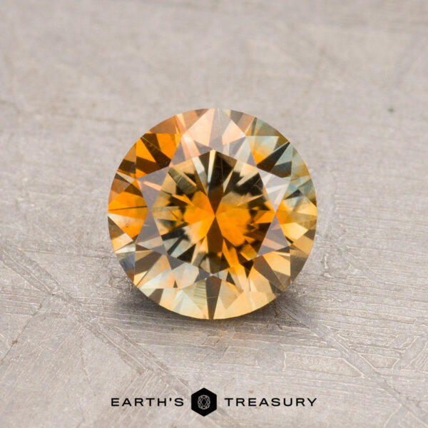 1.11-Carat Montana Sapphire (Heated) showcasing a round, faceted design with captivating yellow and orange hues on its textured surface.