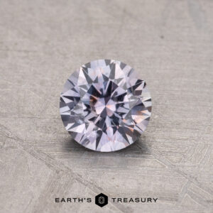 A 0.79-carat heated Montana sapphire rests on a textured surface, showcasing a captivating play of light and colors.