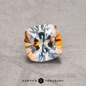 A 0.81-carat Montana Sapphire, featuring a square cushion cut with a blue and orange hue on a textured surface, is labeled "Earth's Treasury.